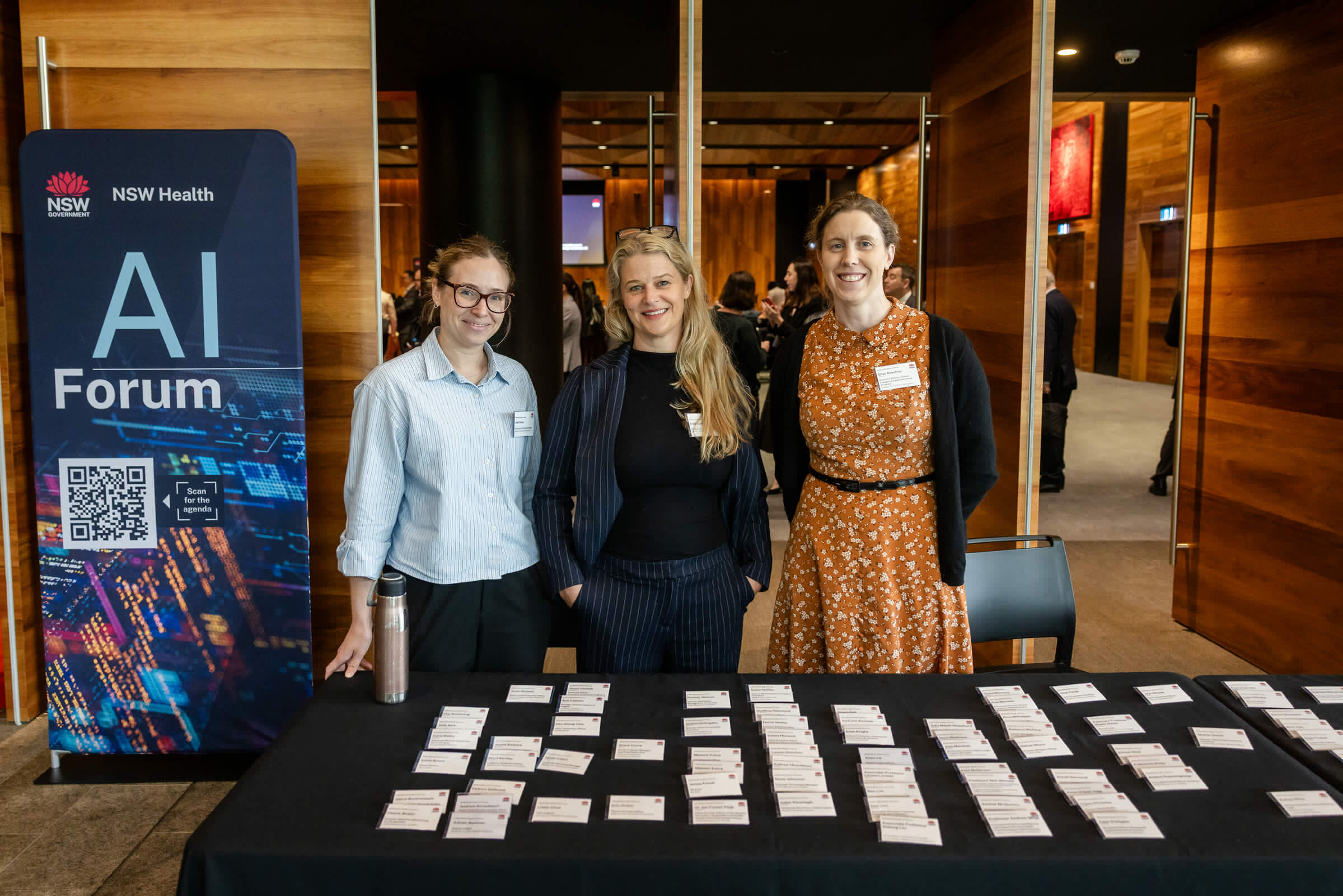 eHealth NSW AI Summit registration team welcoming guests beside the AI Forum sign