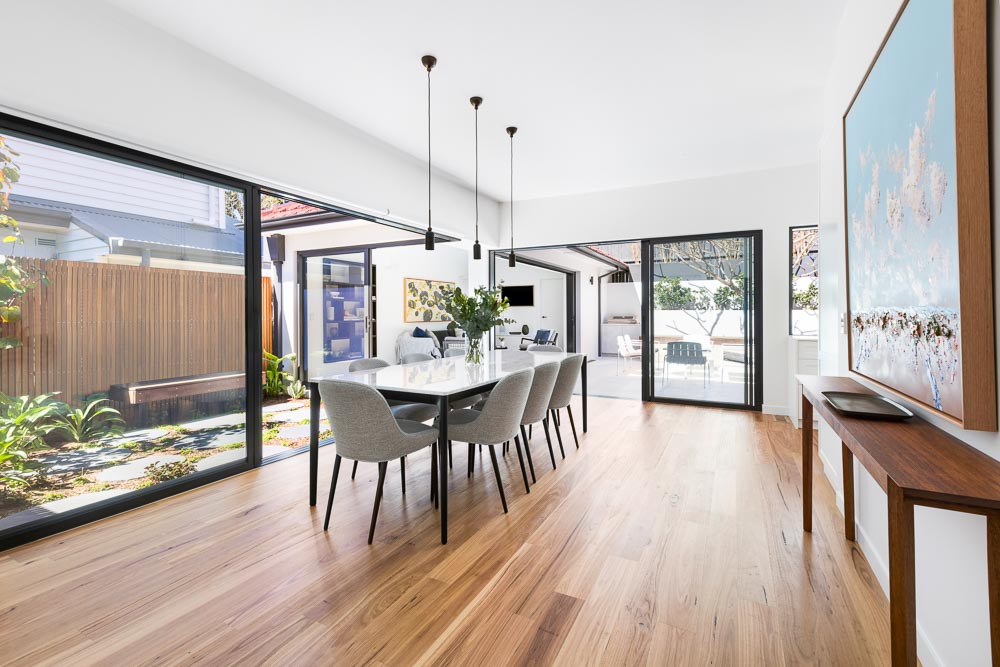 Light-filled dining room with timber flooring and views through the house to the garden
