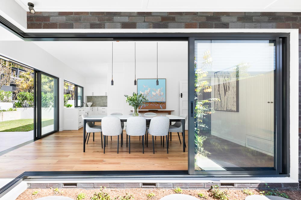 Dining area seen through full-height sliding doors from the landscaped courtyard