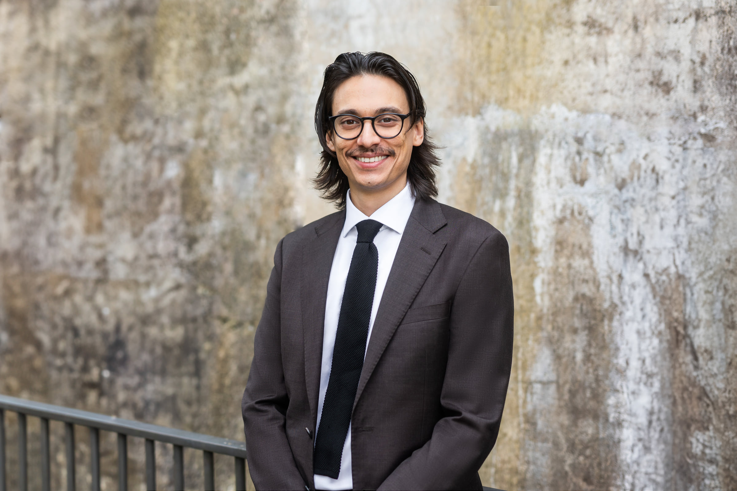 Wider business portrait of Bruce Klaic beside a textured concrete wall