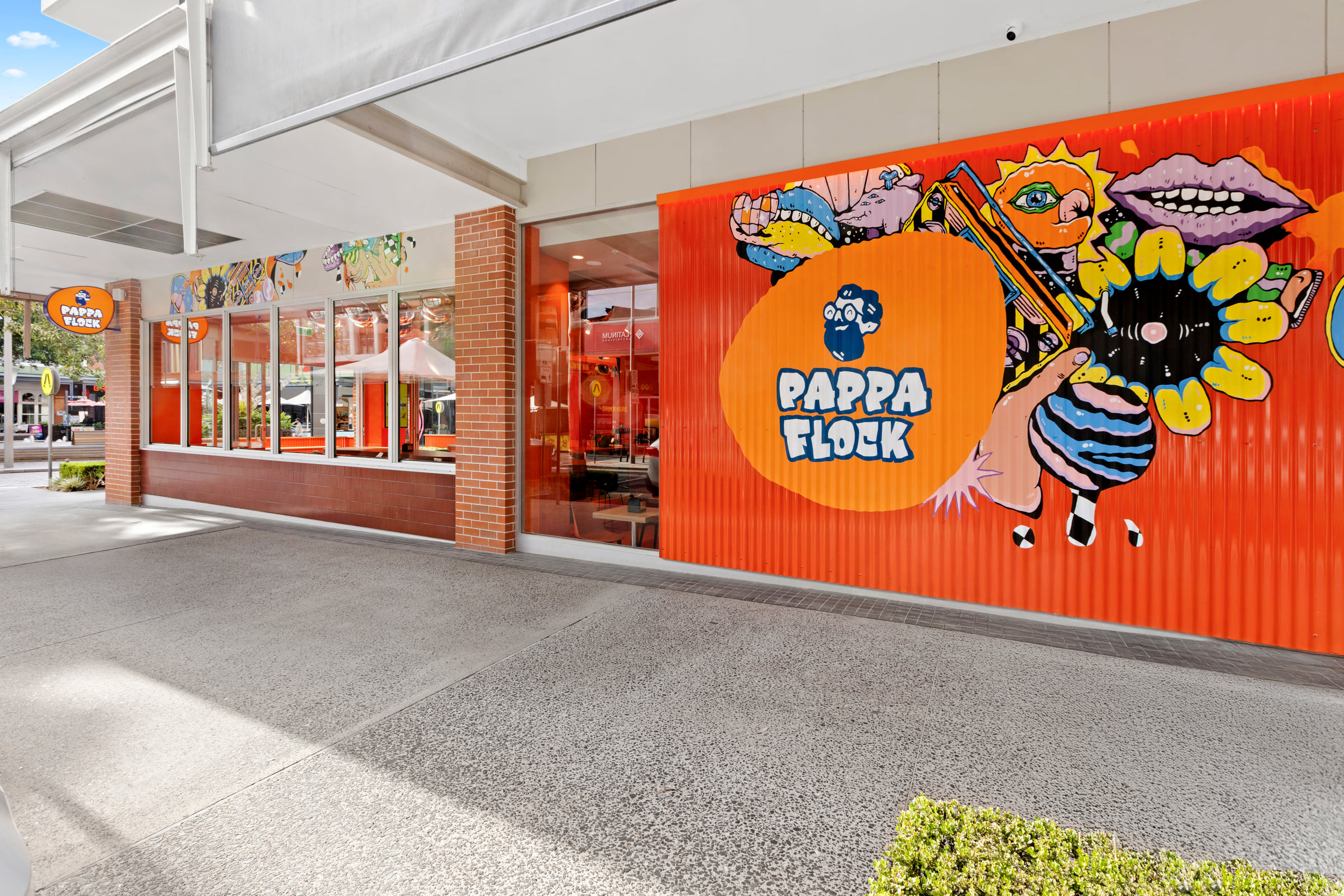 Pappa Flock shopfront wrapped in a colourful mural with orange corrugated cladding