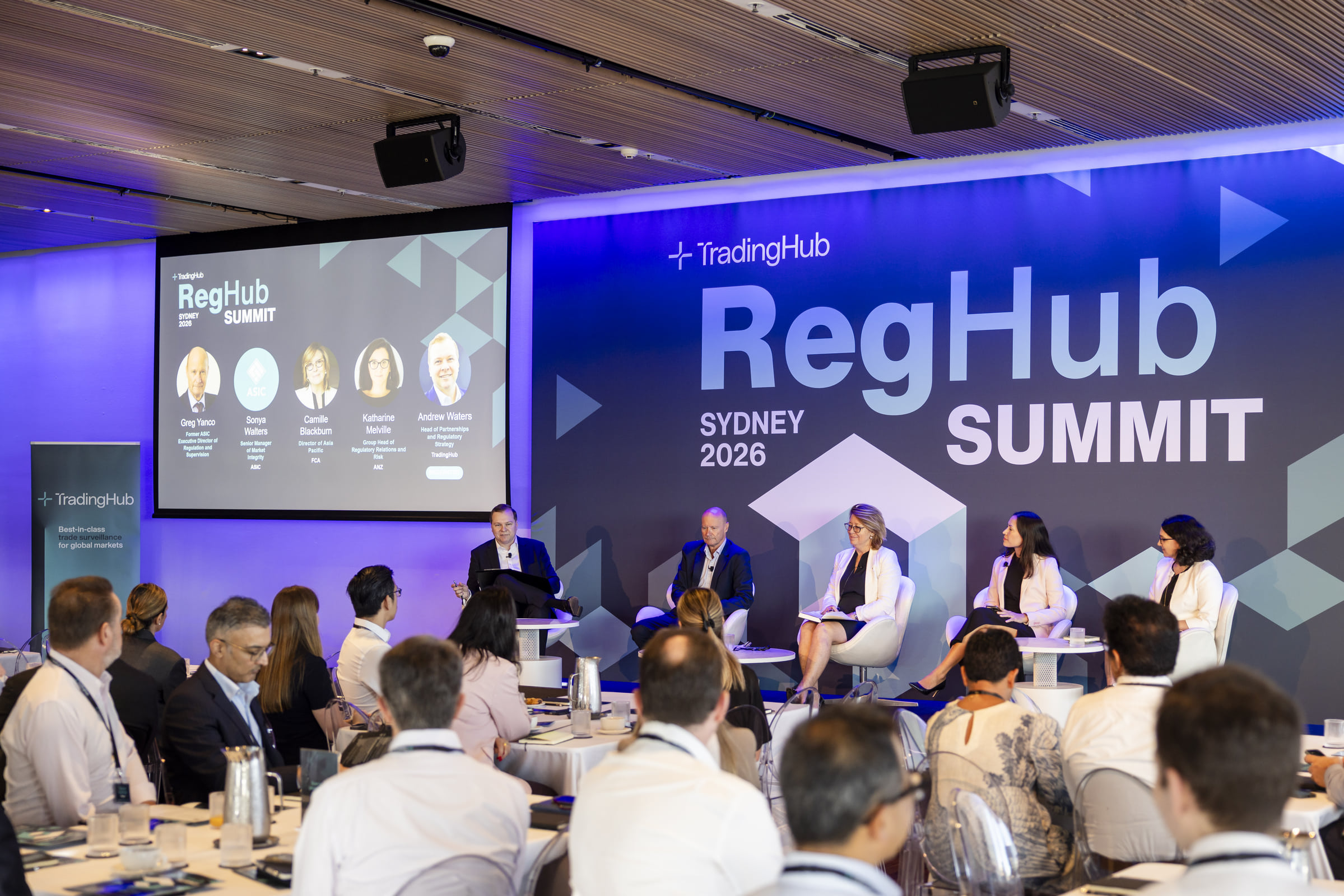 Five panellists on the RegHub Summit stage with attendees seated in the foreground